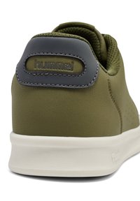 Olivgrüner Sneaker mit einem oberen Teil aus glattem Leder, Mesh-Akzenten und einer gepolsterten Ferse in Dunkelgrau. Mit weißen Gummisohlen und kontrastierenden Nähten.