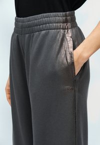 Γκρι παντελόνι φούτερ με υφή, διαθέτει φαρδιά ελαστική μέση, πλαϊνές τσέπες και μικρό λογότυπο στο κάτω μέρος του ποδιού.