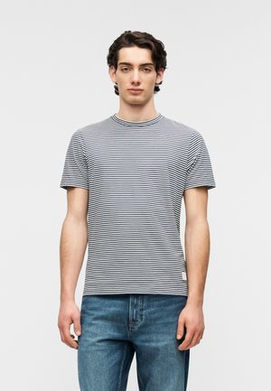 Gestreiftes T-Shirt mit kurzen Ärmeln in Marineblau und Weiß aus Baumwollmischung, Rundhalsausschnitt, strukturierter Stoff, kombiniert mit blauen Denim-Jeans.