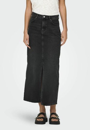 Sort denim maxi nederdel med en frontslids, høj talje og struktureret pasform. Matchet med kraftige sorte sandaler.