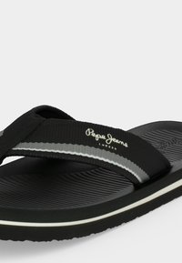 Μαύρα σανδάλια σαγιονάρα με υφασμάτινο λουράκι που φέρει το λογότυπο "Pepe Jeans London", λευκή ρίγα στην άκρη της σόλας και υφή στο πέλμα.