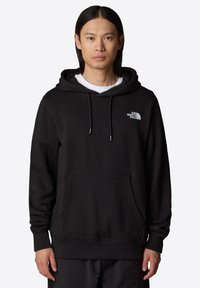 Svart bomullshuvtröja med ficka framtill, snörning i huvan och vit logga på bröstet. Har ribbade muddar och nederkant.