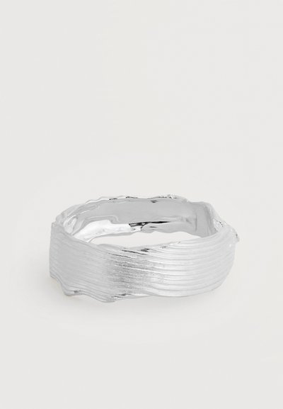Bague en argent texturée avec un design irrégulier et ondulé et une finition brillante et polie sur fond blanc.