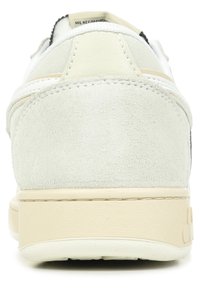 Tennarit, joissa on kermaisen tutkimusyläosan, pyöreä kantapää ja sileä beige pohja. Ominaisuuksiin kuuluu minimaalinen ompelu ja teksturoitu takakoriste.