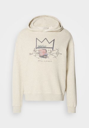 Sudadera con capucha de color beige claro en tela suave, que presenta un diseño gráfico con una corona y detalles en la cara. Mangas con puños y corte relajado.