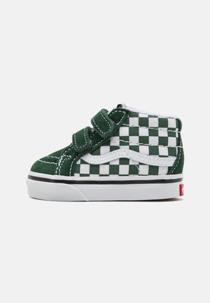 Zapatos de bebé tipo botín de cuadros verdes y blancos con correas de velcro, material de ante, suela de goma blanca y línea de acento negra.