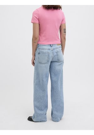Person wearing a pink short-sleeve top and light blue wide-leg jeans, standing with their back facing the viewer against a plain background.