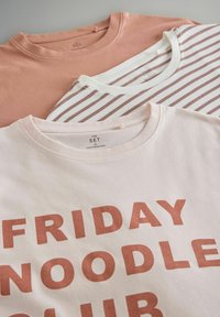 Három pamut póló kiállítva: egy por rózsaszín, egy fehér barna csíkokkal, egy világos rózsaszín, amelyen a "FRIDAY NOODLE CLUB" felirat barna színnel szerepel.