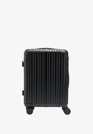 Czarna walizka z twardą skorupą, pionowymi rowkami, wzmocnionymi narożnikami i czterema obrotowymi kółkami dla łatwej mobilności.
