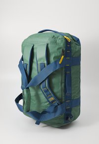 Green fabric duffel bag with blue straps, features yellow zipper accents, rectangular shape, and visible stitching details.