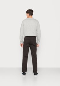Gray sweatshirt with long sleeves, black trousers, and black sneakers, viewed from the back against a plain white background.