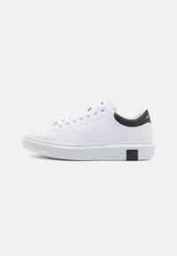 Sneaker bianco con tomaia in sintetico liscia, design a punta rotonda, accentuazione nera nel tallone e chiusura con lacci. Presenta suole testurizzate e un dettaglio con il logo.