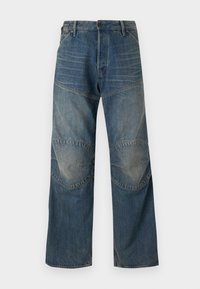 Jean en denim avec une coupe ample, couleur bleu moyen, décoloration visible, coutures en panneaux et renforts aux genoux. Dispose d'une fermeture à bouton et de passants de ceinture.