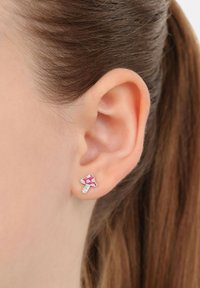 Orecchino a perno a forma di fungo rosa con accenti bianchi, realizzato in metallo. Il design presenta una texture liscia e dettagliati motivi sul cappello.