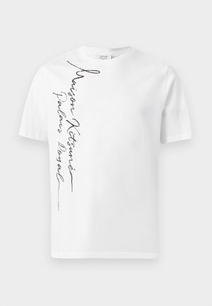 Weißes T-Shirt mit Rundhalsausschnitt, kurzen Ärmeln und vertikalem schwarzen Kursivschrift-Text "Maison Kitsuné Palais Royal" auf der linken Seite.