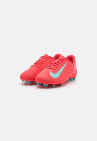 Scarpette da calcio di un rosso brillante con superficie texturizzata, dettagli turchesi e un grande logo Swoosh. Presentano numerosi tacchetti di aderenza per una migliore presa.