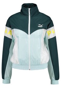 Chubasquero Puma que presenta una combinación de colores en verde azulado y azul claro, con cierre de cremallera, cuello alto y puños y dobladillo elásticos.