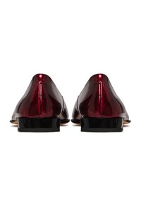 Mocassins en cuir verni bordeaux avec un petit talon noir et une texture lisse, présentant un bout arrondi et un design minimaliste.