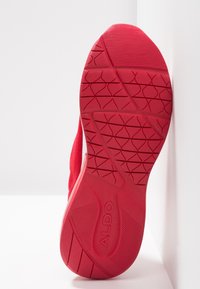 Červená sportovní boty podrážka, vyrobená z gumy s texturovanými vzory pro lepší grip. Obsahuje logo a hladké akcenty podél okrajů.