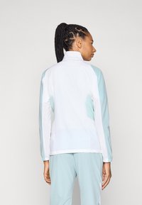 Leichte Sportjacke in Weiß und Teal, mit hohem Kragen, langen Ärmeln und einer taillierten Passform mit strukturierten Stoffakzenten.