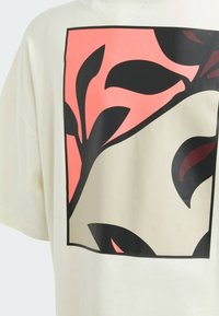 Creme bomulds T-shirt med et stort grafisk design af sorte blade på en pink baggrund inden for en firkantet ramme. Løs pasform.