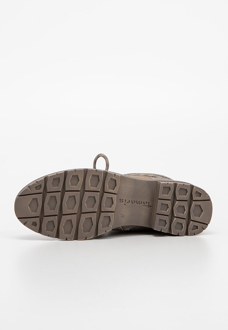 Bruine schoenen met een gemetste rubberen zool, voorzien van hexagonale patronen voor grip. Inclusief een trekband aan de achterkant voor gemakkelijk aan- en uittrekken.