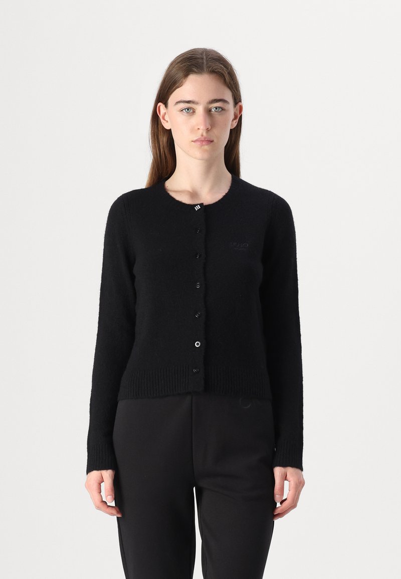 Cardigan nero realizzato in materiale pelucchioso. Presenta un colletto rotondo, maniche lunghe e chiusura con bottoni. Design a maglia semplice con dettagli a coste.