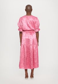 Rosa satengkjole med korte pufferm, blomsterdesign, innsamlet midje og lagdelt skjørt. Glatt tekstur, kne-lengde, beskjeden stil.