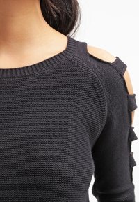 Czarny sweter z dzianiny z wycięciami na ramionach, wykonany z teksturowanej włóczki i z ribbowym dekoltem. Dekoracyjne akcenty na rękawach dodają szczegółów.