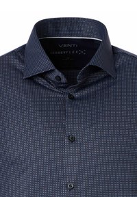 Marineblauwe overhemd met knopen en kleine geometrische patronen in lichtblauw en wit. Heeft een gespreide kraag en zwarte knopen. Zacht jersey stof.