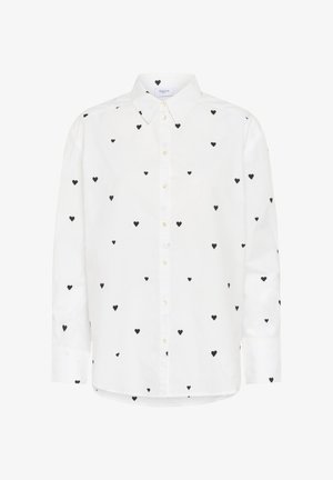 Balta krekla ar apkakli, kuram visā virsmā ir melni sirdītes raksti. Izgatavots no kokvilnas, ar brīvu piegriezumu un taisnu apakšmalu.