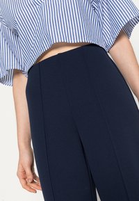 Blå och vit randig kortärmad blus med volangärm, ihop med marinblå högmidjade byxor med framveck.