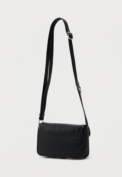 Μαύρη τσάντα χιαστί από λεία υφή, ορθογώνιο σχήμα, με ρυθμιζόμενο ιμάντα με μοτίβο και κομψό, μινιμαλιστικό σχεδιασμό.