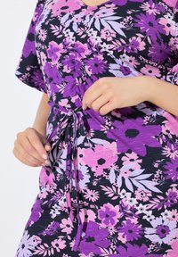 Květinové šaty s mixem fialových, růžových a levandulových odstínů, s výstřihem do V, krátkými rukávy a detailem na vázání v pase.