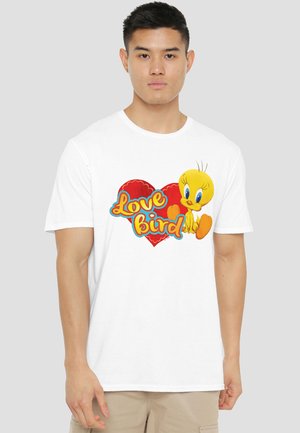 Young man wearing a white T-shirt with a red heart and yellow cartoon bird with the words "Love bird" printed on the front.
