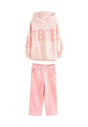 Ensemble de sweat à capuche rose clair et pantalon assorti. Le sweat à capuche présente une coupe surdimensionnée, des poignets élastiques et le logo "TB". Le pantalon a une taille élastique et des poches.