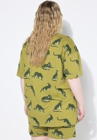 Set da casa in cotone verde oliva composto da una maglietta ampia e pantaloni corti, decorato con ripetuti motivi a leopardo in verde scuro e bianco.