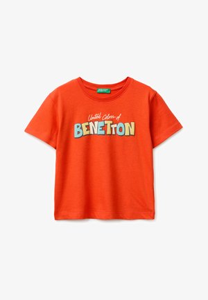 Jasnopomarańczowa koszulka z krótkim rękawem z kolorowym napisem „United Colors of Benetton” na piersi oraz zieloną metką marki wewnątrz kołnierza.