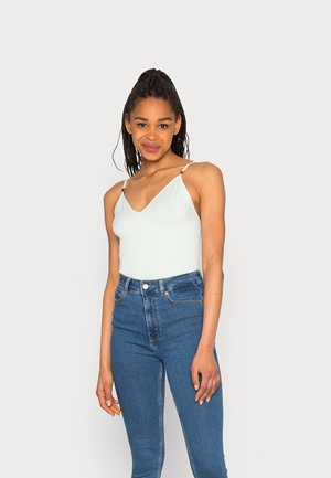 Bodies azul claro com nervuras, com decote em V e alças finas, combinado com jeans escuros de cintura alta. Barra semelhante a saia e acessórios de prata simples.