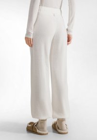 Vita, högmidjade sweatpants med en ribbad midja, mjuk textur, vida ben och en subtil rosa detalj på den bakre midjan.