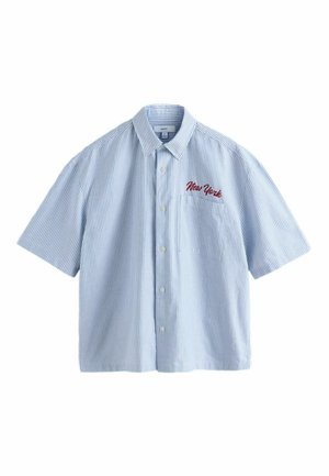 Rövid ujjú, gombos ing világoskék és fehér csíkokkal. A bal mellzseben piros, hímzett "New York" felirattal.