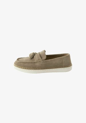Mocassin en suède beige avec un bout arrondi, un gland décoratif et une semelle en caoutchouc blanc. Comprend des détails de couture et une texture lisse.