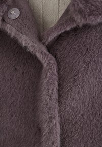 Lila Kunstpelzjacke mit strukturiertem Finish, ausgestattet mit einem breiten Kragen und einem Knopfverschluss. Weiches, flauschiges Material mit glattem Innenfutter.