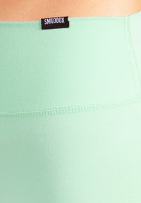 Ljusgröna leggings i mjukt, stretchigt material med en slät struktur. Har en svart etikett i midjan med varumärkets namn.