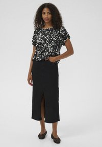 Black floral short-sleeve top paired with a long black denim skirt featuring a front slit. Worn with black perforated flats.
