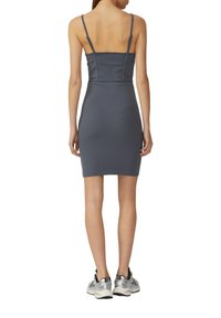 Graues geripptes Bodycon-Kleid mit dünnen Trägern, figurbetonte Silhouette, knielang, kombiniert mit silbernen Sneakers. Glatte Textur, minimalistische Details.