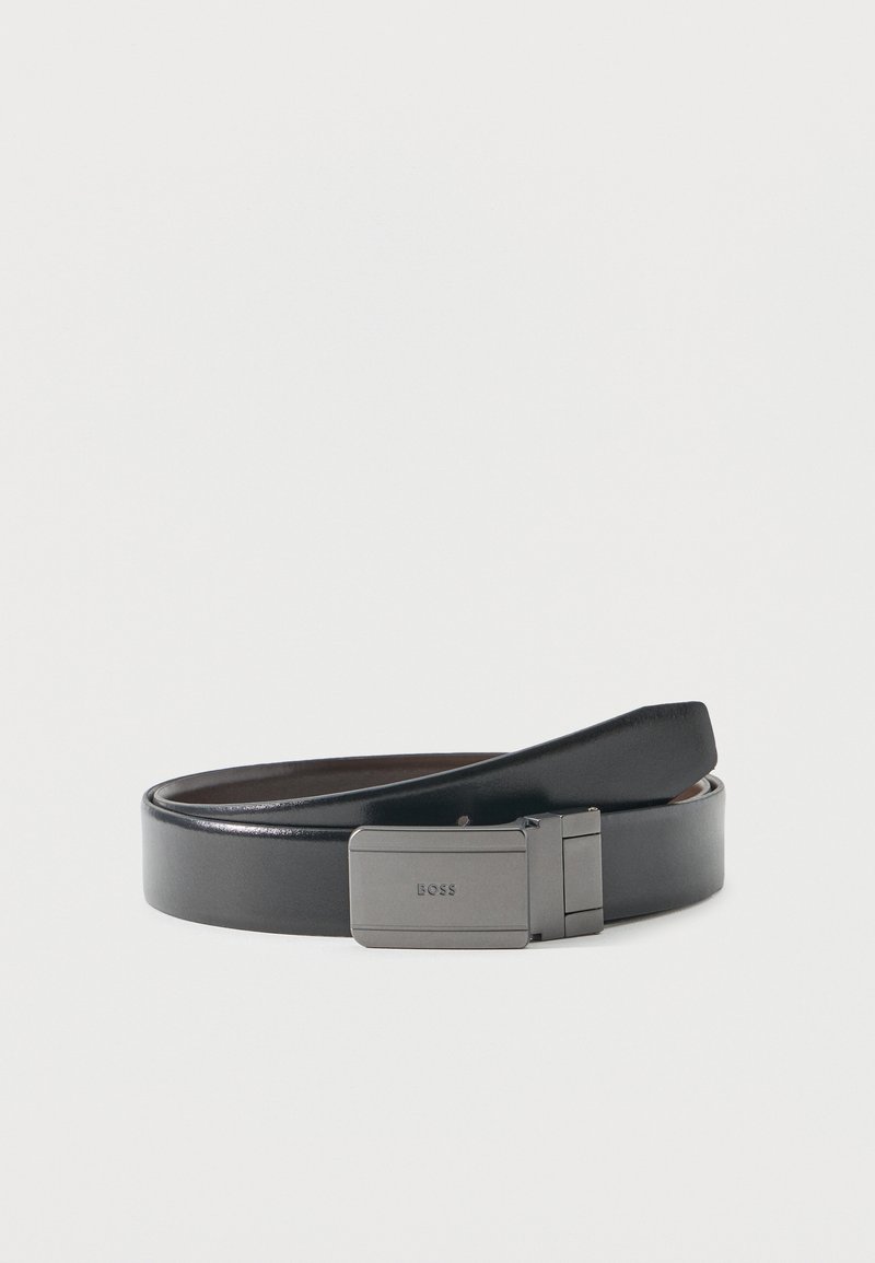 Ceinture en cuir noir avec une boucle rectangulaire en argent gravée "BOSS", disposée en spirale lâche sur un fond blanc uni.