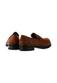 Mocassins en suède marron avec une sangle à l'avant, dotés d'une semelle en caoutchouc noire et d'un dessous texturé pour une meilleure adhérence. Vue arrière présentée.