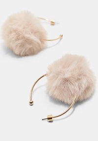 Faux fur hoop øreringe i blød beige. Rundt, fluffy design med metalaccent i guld-tone og en buet tråd, der sikrer en sikker bæring.