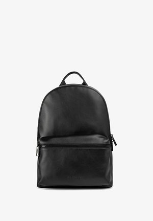 Mochila de cuero negro con una parte superior redondeada, bolsillo frontal con cremallera y detalles de costura. Presenta un asa superior y un logo grabado en la parte inferior frontal.